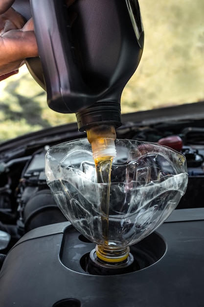 Changer l'huile moteur dans le moteur de la voiture de vos propres mains Un homme verse de l'huile neuve à partir d'un bidon