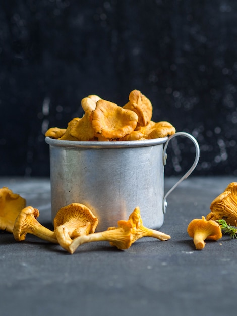 Chanterelles fraîches dans une tasse en métal sombre.