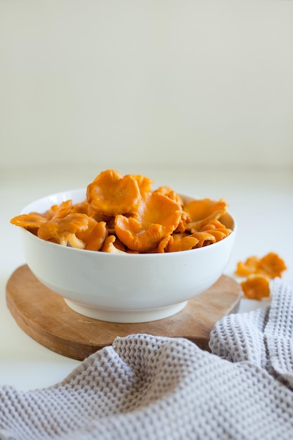 Chanterelles rouges dans une assiette blanche sur une table gris clair