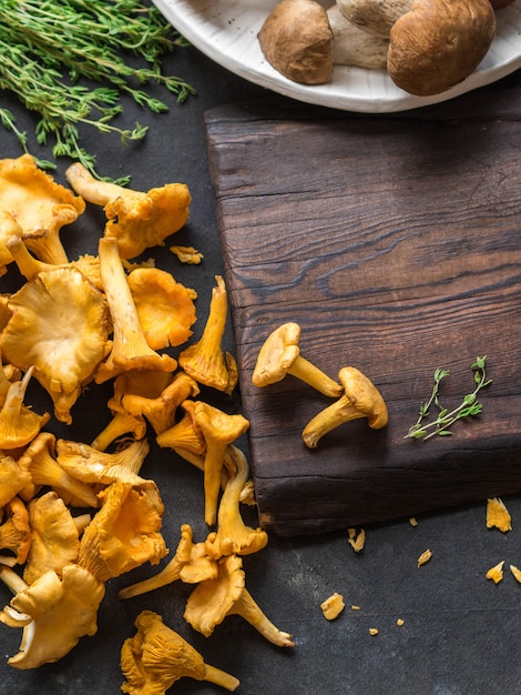 Chanterelles sauvages crues et cèpes crus à côté d'un tableau noir.