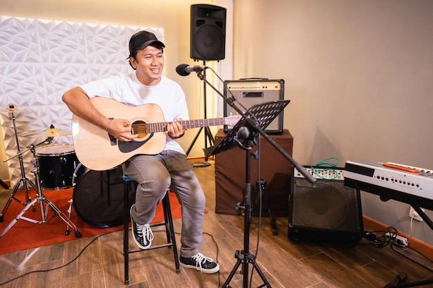 Un chanteur chante en jouant de la guitare acoustique avec des instruments de musique en arrière-plan