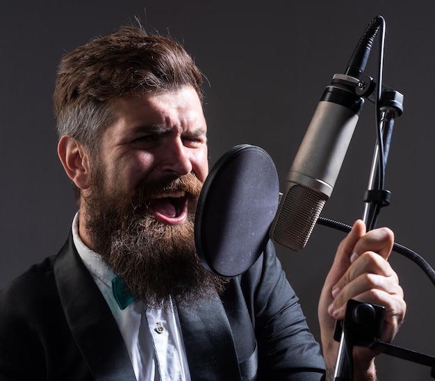 Le chanteur classique interprète une chanson avec un microphone tout en enregistrant dans un studio de musique