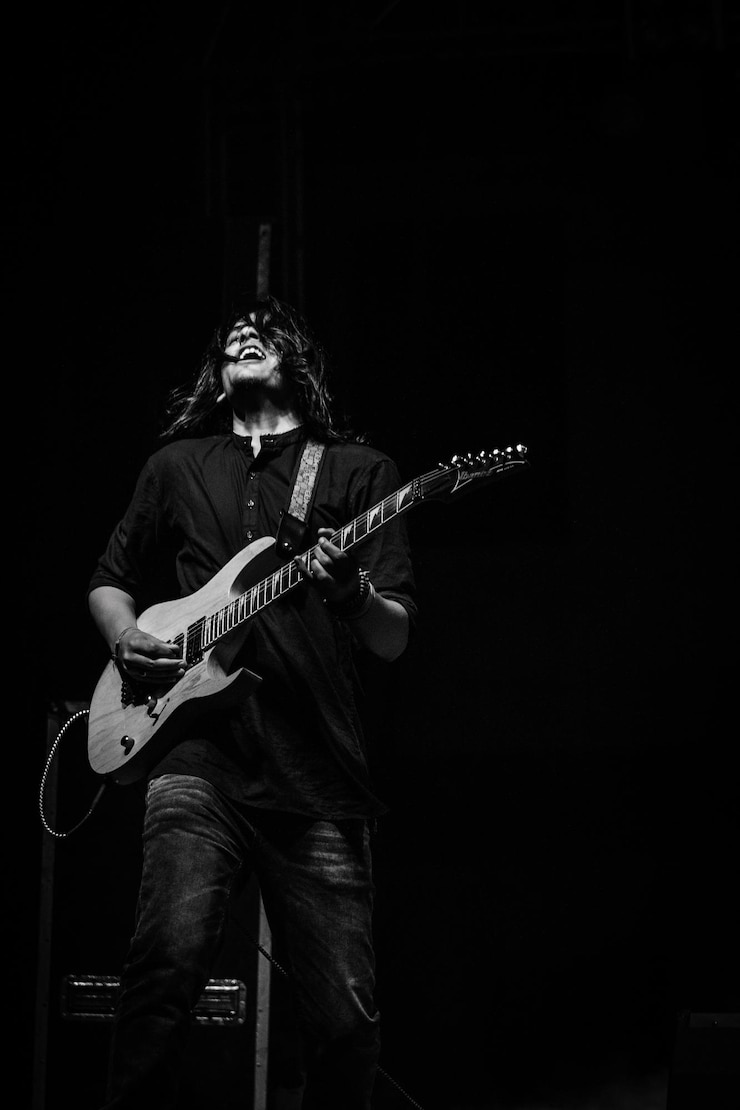 Photo chanteur jouant de la guitare tout en chantant sur un fond noir