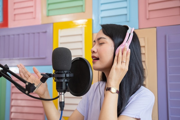 Chanteur portant des écouteurs chantant à l'aide d'un microphone sur fond de mur en bois coloré