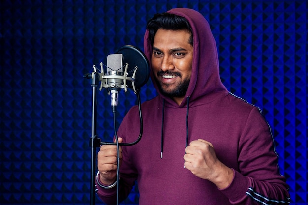 Chanteur professionnel hommes indiens écouteurs son studio moderne violet fond chanson d'enregistrement