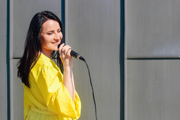 Une chanteuse aux cheveux noirs dans une robe tient un microphone dans ses mains