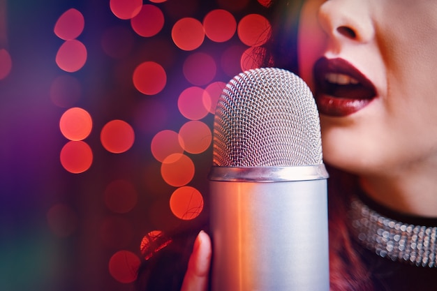 Chanteuse avec micro disco sur fond clair bokeh gros plan des lèvres des femmes peintes de bordeaux ...