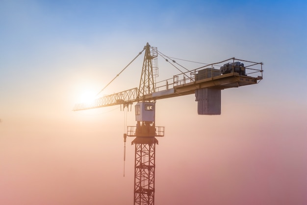 Chantier de construction à l'aube. Grues à tour sur le brouillard sur le fond du soleil du matin. Vue drone