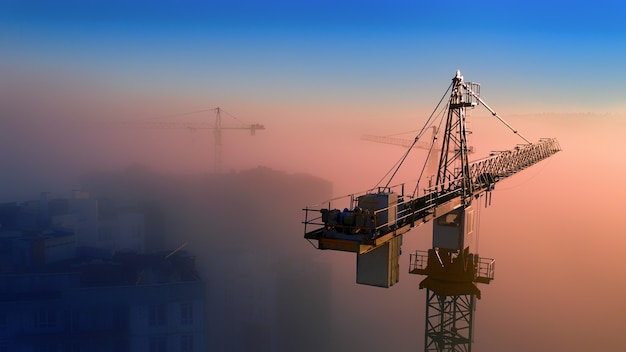 Chantier de construction à l'aube. Grues à tour sur le brouillard sur le soleil du matin. Vue drone