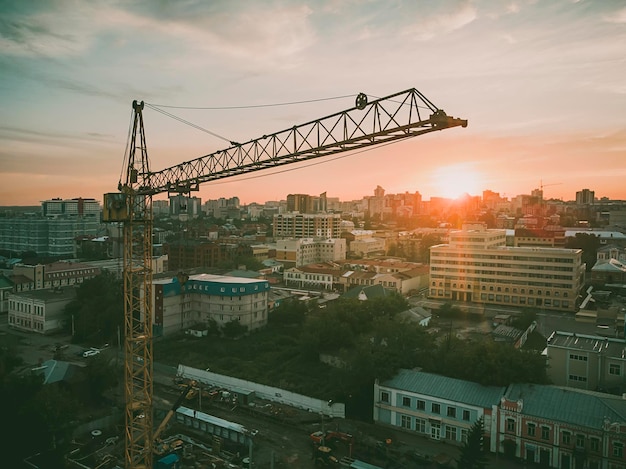 Chantier de construction avec bloc de grande hauteur en construction dans un environnement urbain dominé par une grande grue industrielle se découpant sur un ciel bleu nuageux.