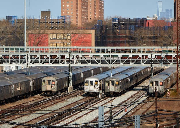 Le chantier ferroviaire de Coney Island avec plusieurs trains NYC garés et des gratte-ciel visibles en arrière-plan