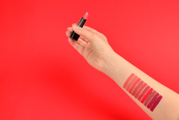 Échantillons de rouge à lèvres sur la main de la femme isolée sur fond rouge