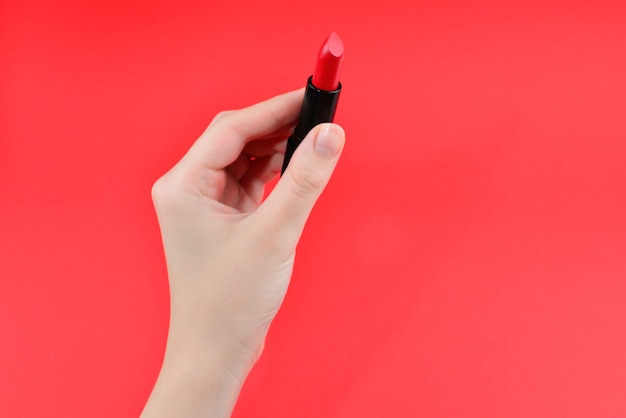 Échantillons de rouge à lèvres sur la main de la femme isolée sur fond rouge.