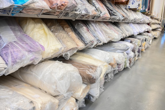 Échantillons de rouleaux de tissu dans l'entrepôt Les rouleaux de tissu sont emballés dans des sacs en plastique Entrepôt de tissu avec de nombreux rouleaux de textile