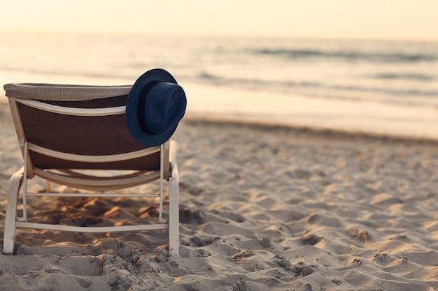 Chapeau bleu allongé sur une chaise longue sur la plage