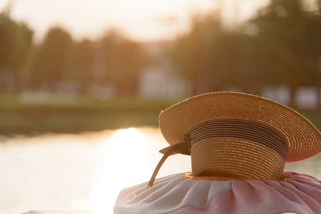 Photo chapeau brun au jardin parc et rivière dans la soirée avec l'heure du coucher du soleil.