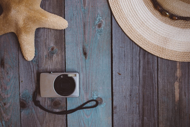 Un chapeau, une caméra, une étoile de mer, sur le fond en bois