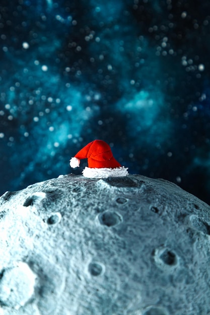 Chapeau du père Noël sur la lune dans le contexte du ciel étoilé de la nuit