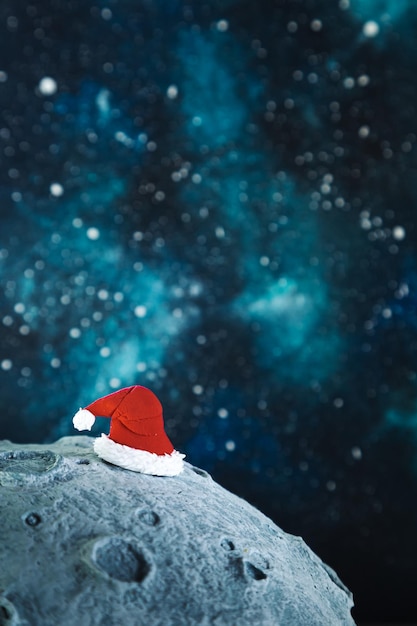 Chapeau du père Noël sur la lune dans le contexte du ciel étoilé de la nuit