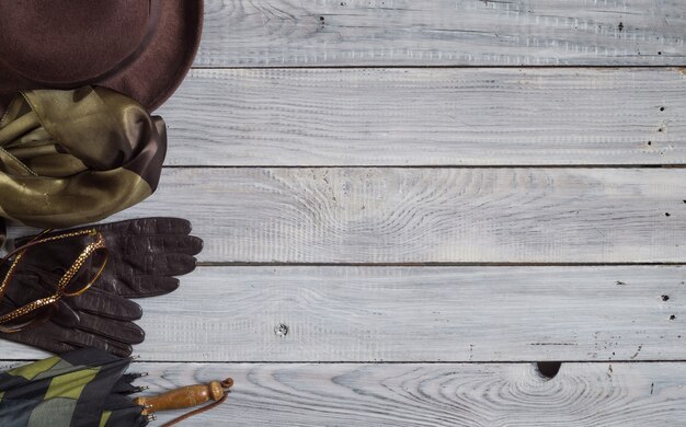 Chapeau féminin et accessoires rétro pour voyager sur une surface en bois peinte en blanc