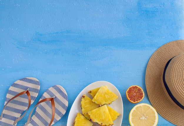 chapeau femme, tongs, assiette de fruits coupés