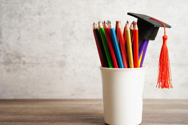 Chapeau de graduation avec des crayons colorés sur livre avec copie espace apprentissage concept d'enseignement universitaire