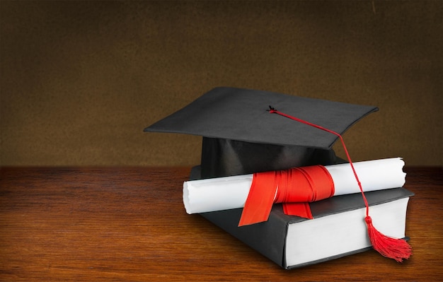 Chapeau de graduation et diplôme sur fond de bois