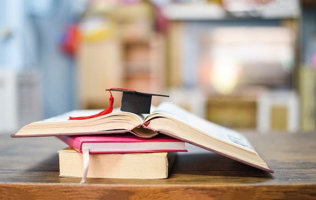 chapeau de graduation sur un livre sur la table en bois