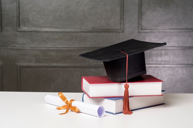 Chapeau de graduation avec des livres sur un bureau blanc, fond d'éducation