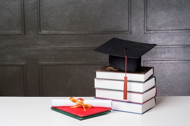 Chapeau de graduation avec des livres sur un bureau blanc, fond d'éducation