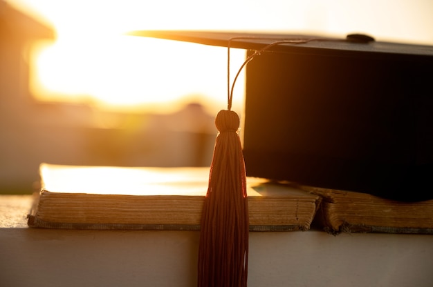 chapeau de graduation noir avec des glands bruns placés sur des livres