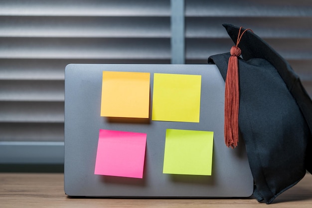 Chapeau de graduation et ordinateur portable et collection de notes collantes colorées post-it papier note fond isolé