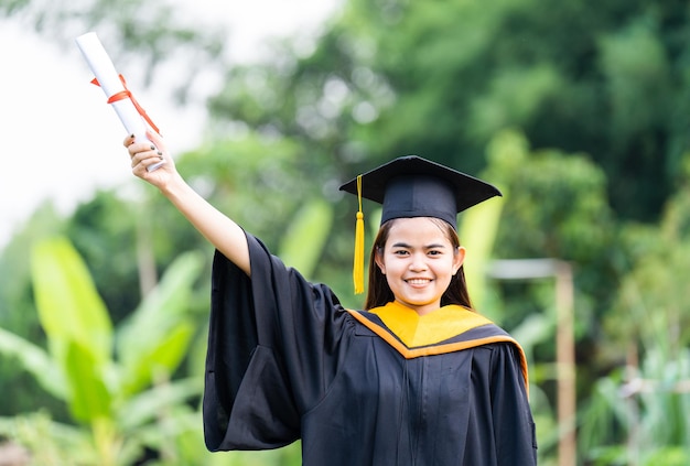 Chapeau de graduation avec pompon en or tenant un diplôme diplômés de l'université Concept félicitations aux diplômés de l'éducation à l'université