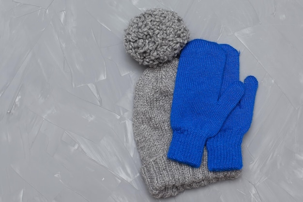 Un chapeau d'hiver et des mitaines attachées ensemble se trouvent sur un fond gris Vue d'en haut Vêtements d'hiver en laine