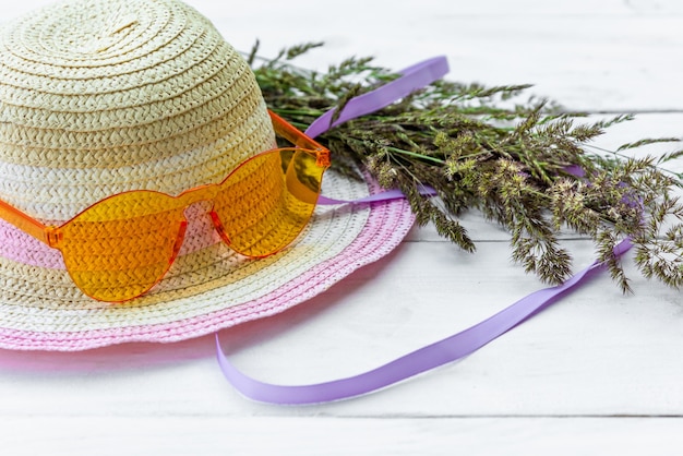 Un chapeau avec des lunettes et un bouquet d'herbe, le concept de vacances d'été dans le village.