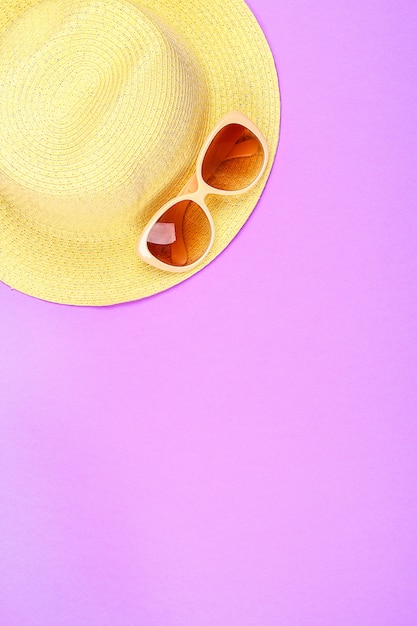 Photo chapeau, lunettes de soleil sur fond rose pastel, violet.