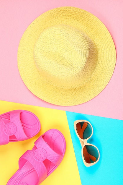 Chapeau, lunettes de soleil et pantoufles sur un fond pastel tricolore