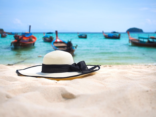 Chapeau de paille blanc sur la plage de sable avec fond de paysage marin pour le concept de vacances d'été