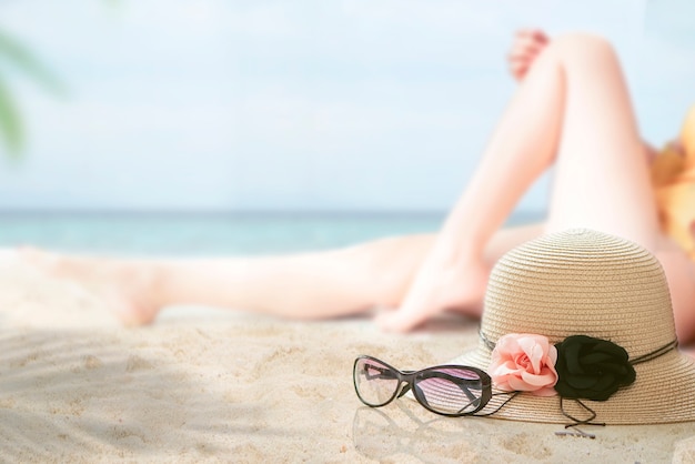 Chapeau de paille et lunettes sur la plage avec l&#39;image floue de la femme en bikini