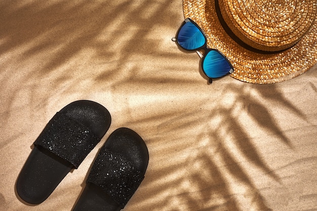 Chapeau de paille sandale et lunettes de soleil sur fond de sable