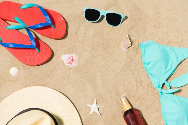 Chapeau de paille, tongs et lunettes de soleil sur le sable de la plage