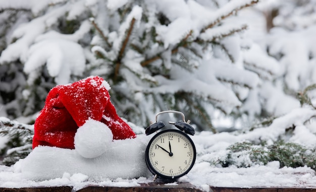 Chapeau de père Noël et réveil vintage en table en bois en blizzard