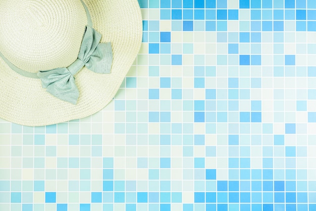 Chapeau de plage sur des carreaux de céramique bleue à la piscine.