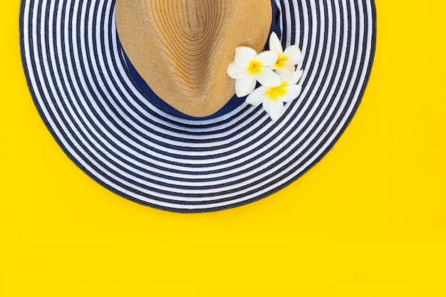 Photo chapeau rayé et fleurs isolés sur jaune