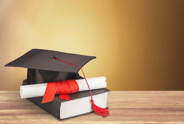 Chapeau de remise des diplômes, livre et diplôme sur table en bois