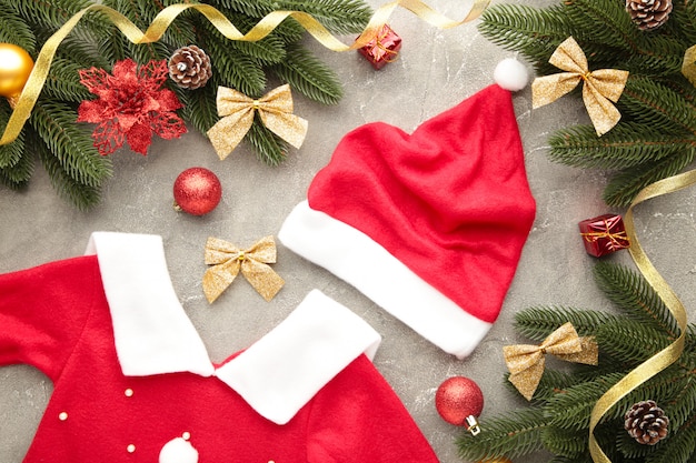 Chapeau et robe rouge du père Noël avec décoration sur fond gris.