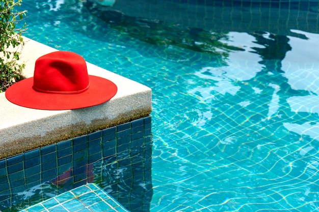 Chapeau rouge sur la piscine d&#39;eau bleue