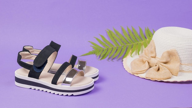 Chapeau de sandales pour femmes blanches et noires et feuille de palmier sur fond violet