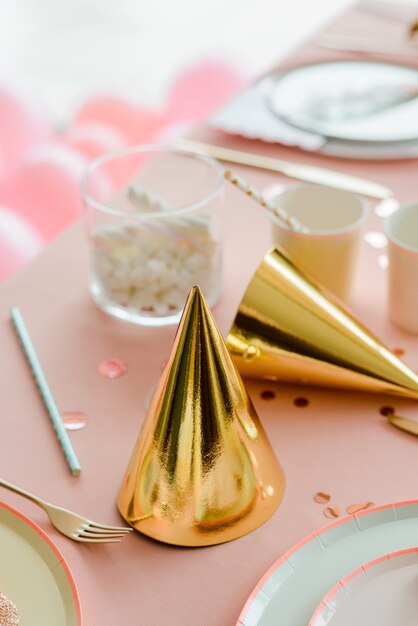 Chapeaux d'anniversaire d'or sur la table de fête rose