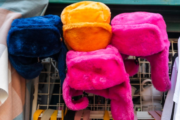 Chapeaux de fourrure de couleur vive avec oreillettes sur le comptoir du vendeur de rue